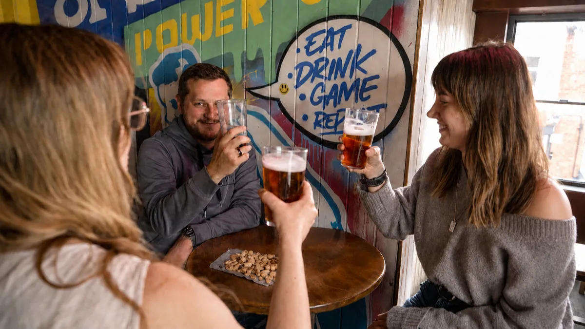 Friends raising pints together in a pub