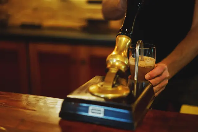Bartender pouring beer in a glass using the beer pump